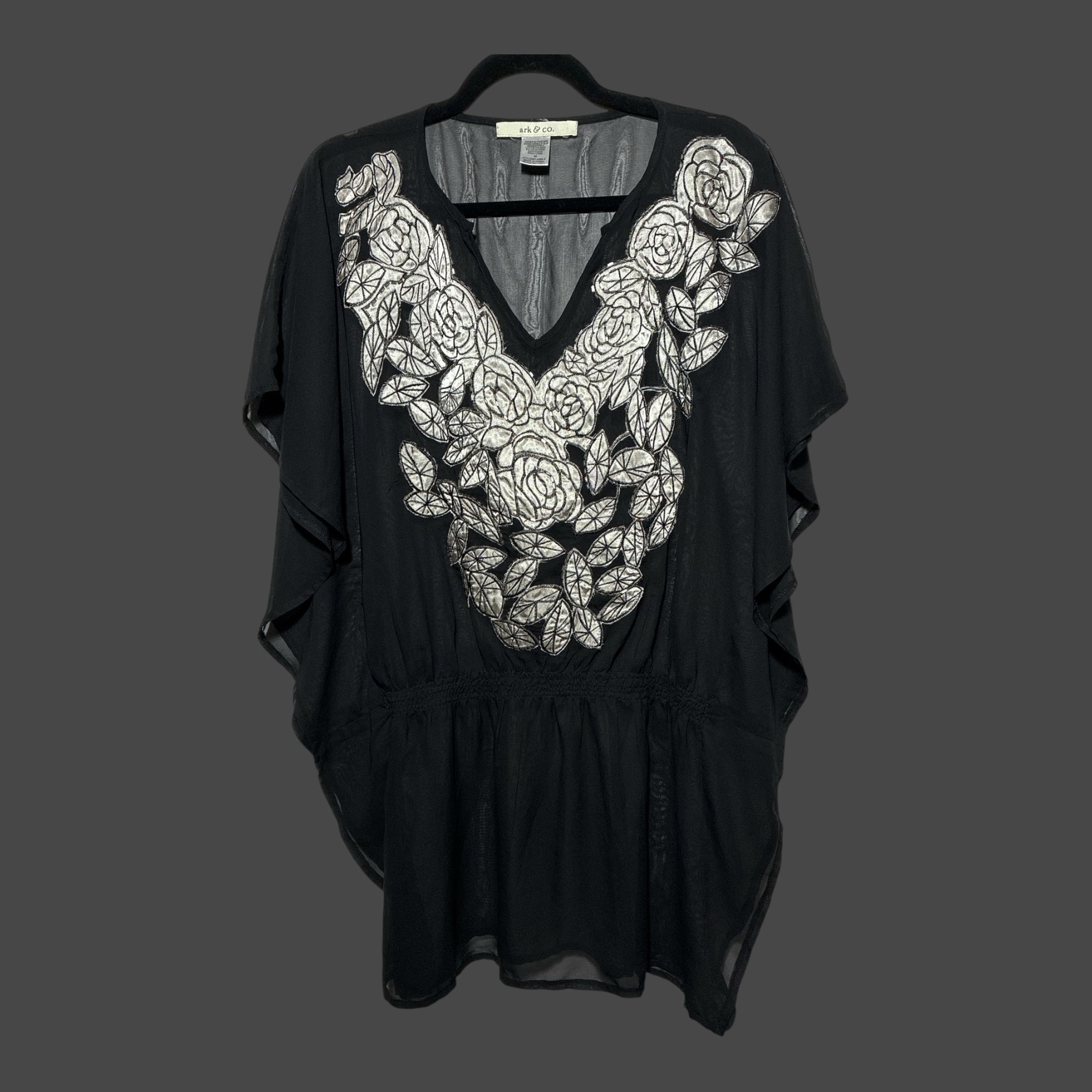 But I Wish It Was Black sheer black tunic with white floral embroidery, V-neck, and flutter sleeves on a hanger.